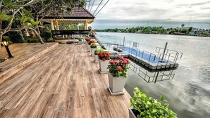 Una terraza de madera con plantas en macetas y un área de piscina pequeña con vista a una masa de agua.