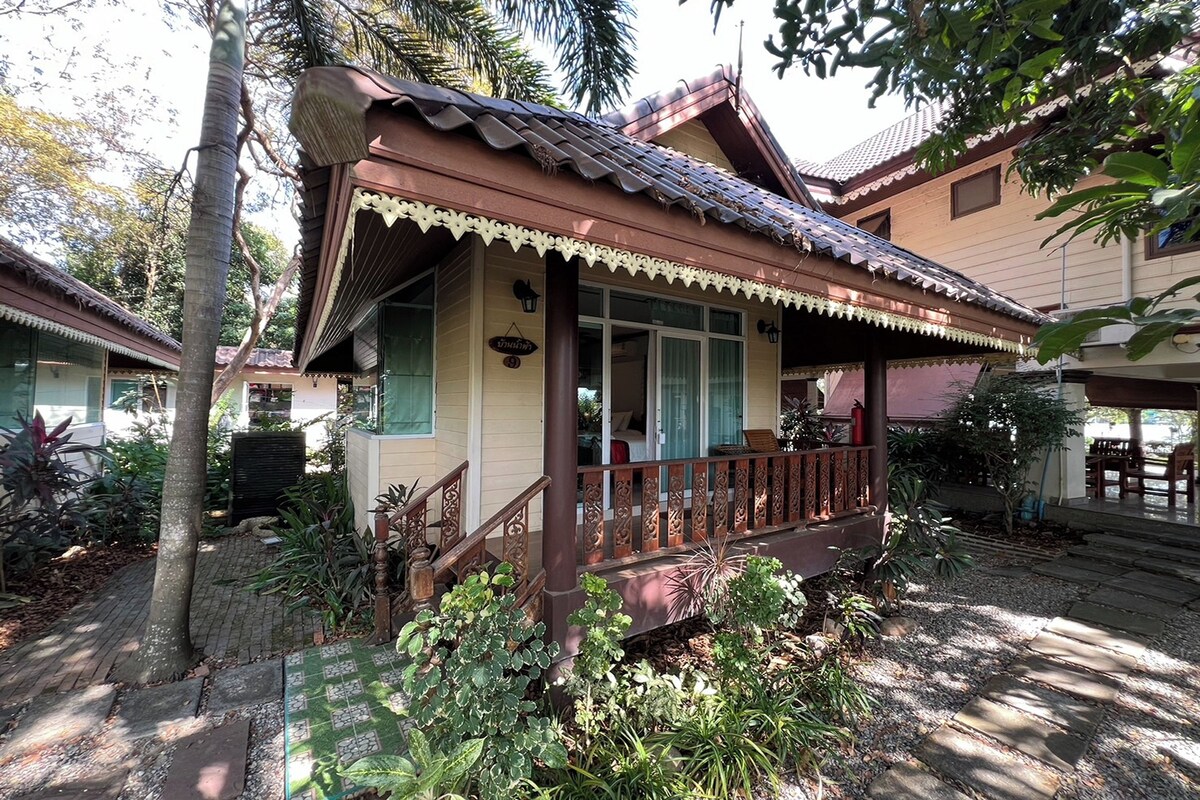 A traditional house with a porch, a staircase, and a garden with various plants.