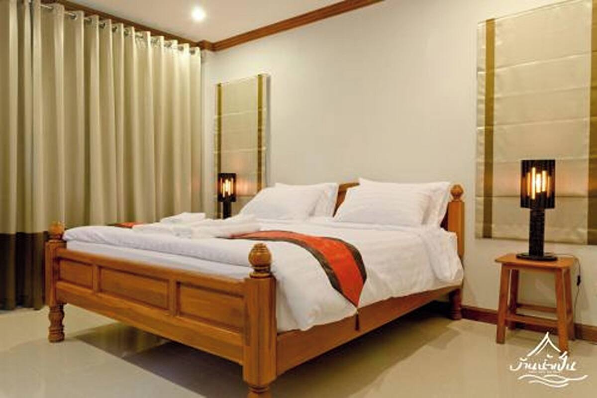 A hotel room with a wooden bed, beige curtains, and two bedside lamps.