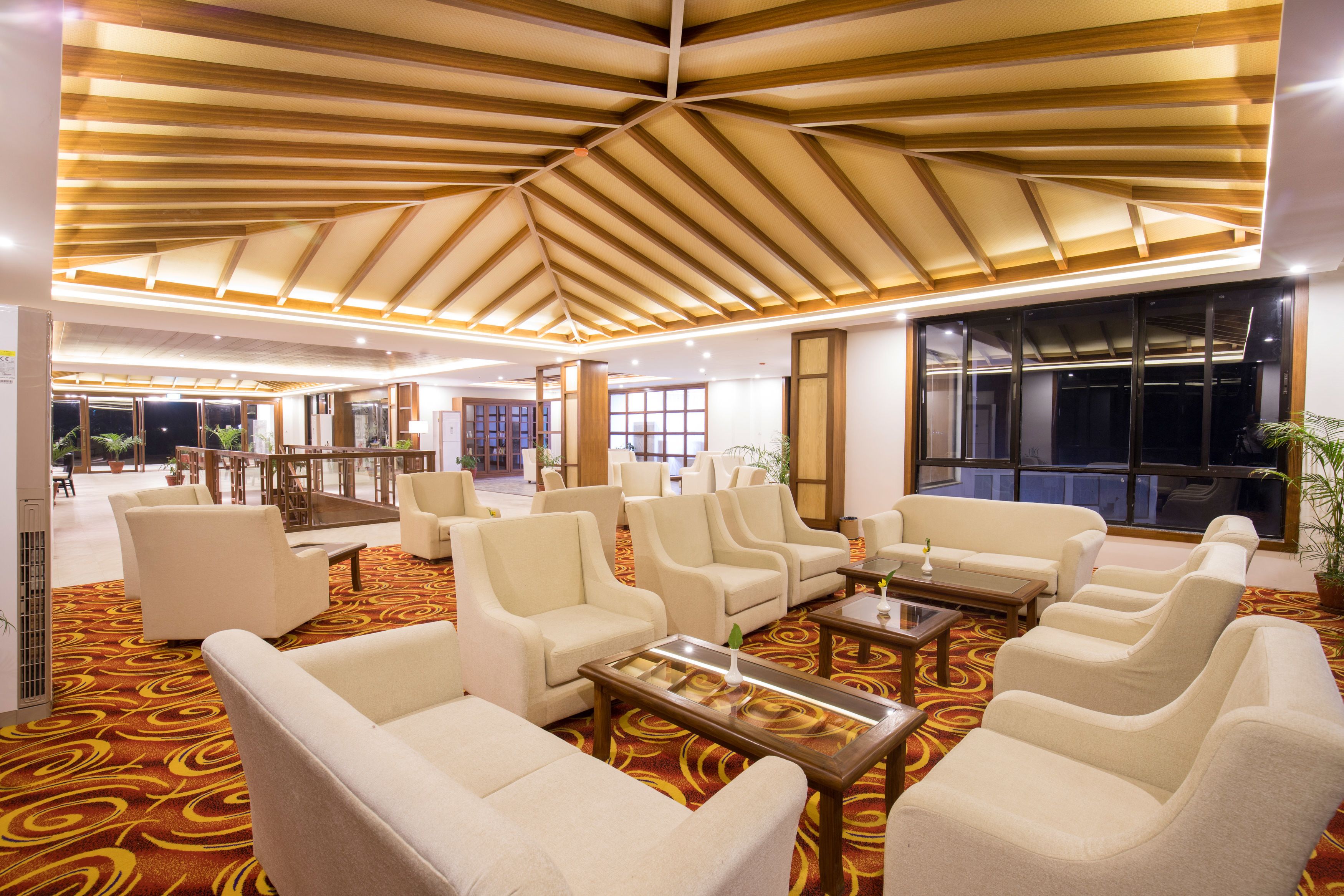 A hotel lobby with a high ceiling, multiple seating areas, and large windows.
