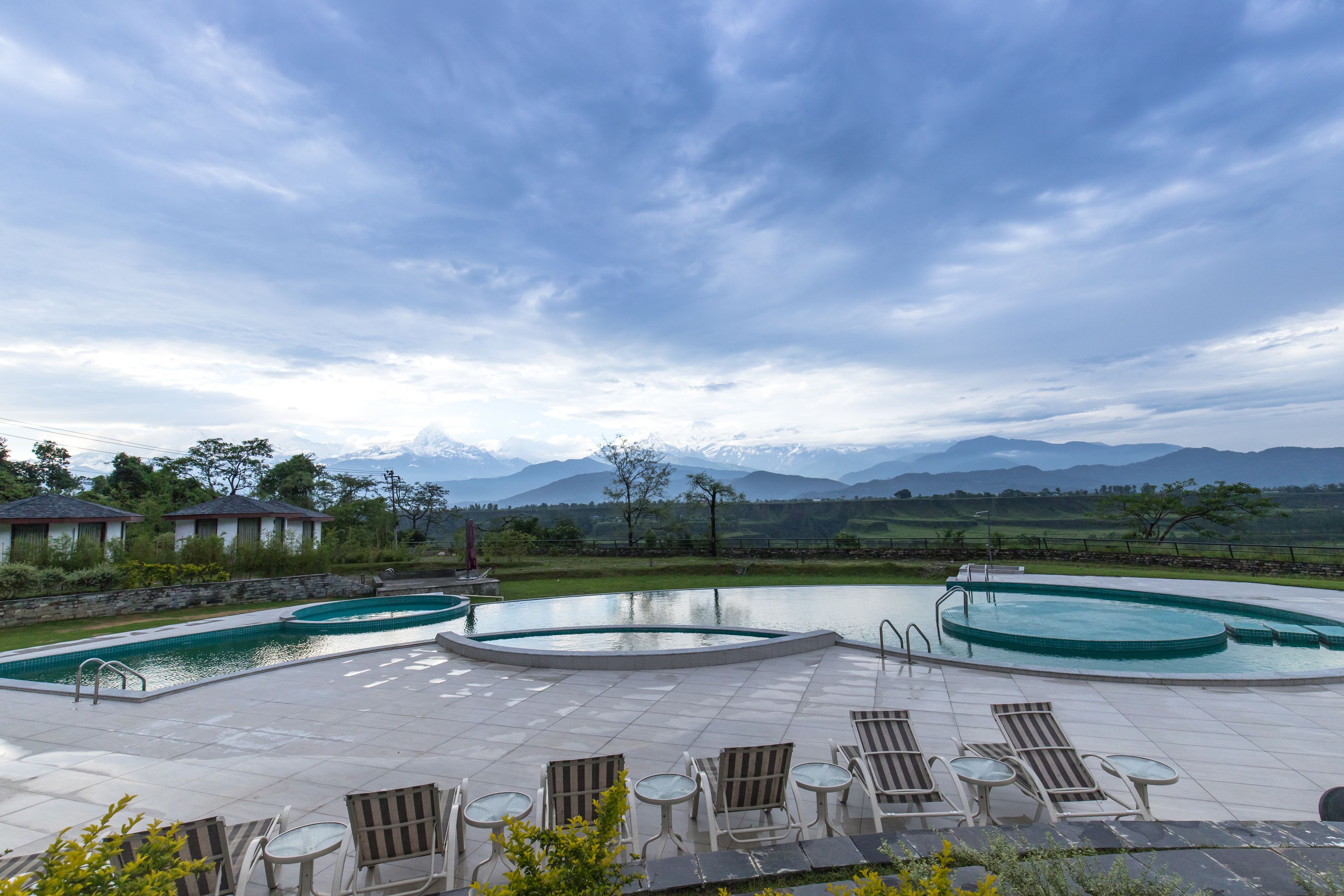 A pool area with lounge chairs and a view of mountains.