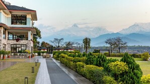 A hotel with a modern design, a covered outdoor area, and a view of snow-capped mountains. - Mountain Glory Forest Resort and Spa, Pokhara (Pokhara)