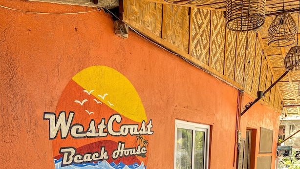 L’intérieur d’une maison de plage, avec une fresque représentant une scène de plage, des bancs en bois et des coussins.