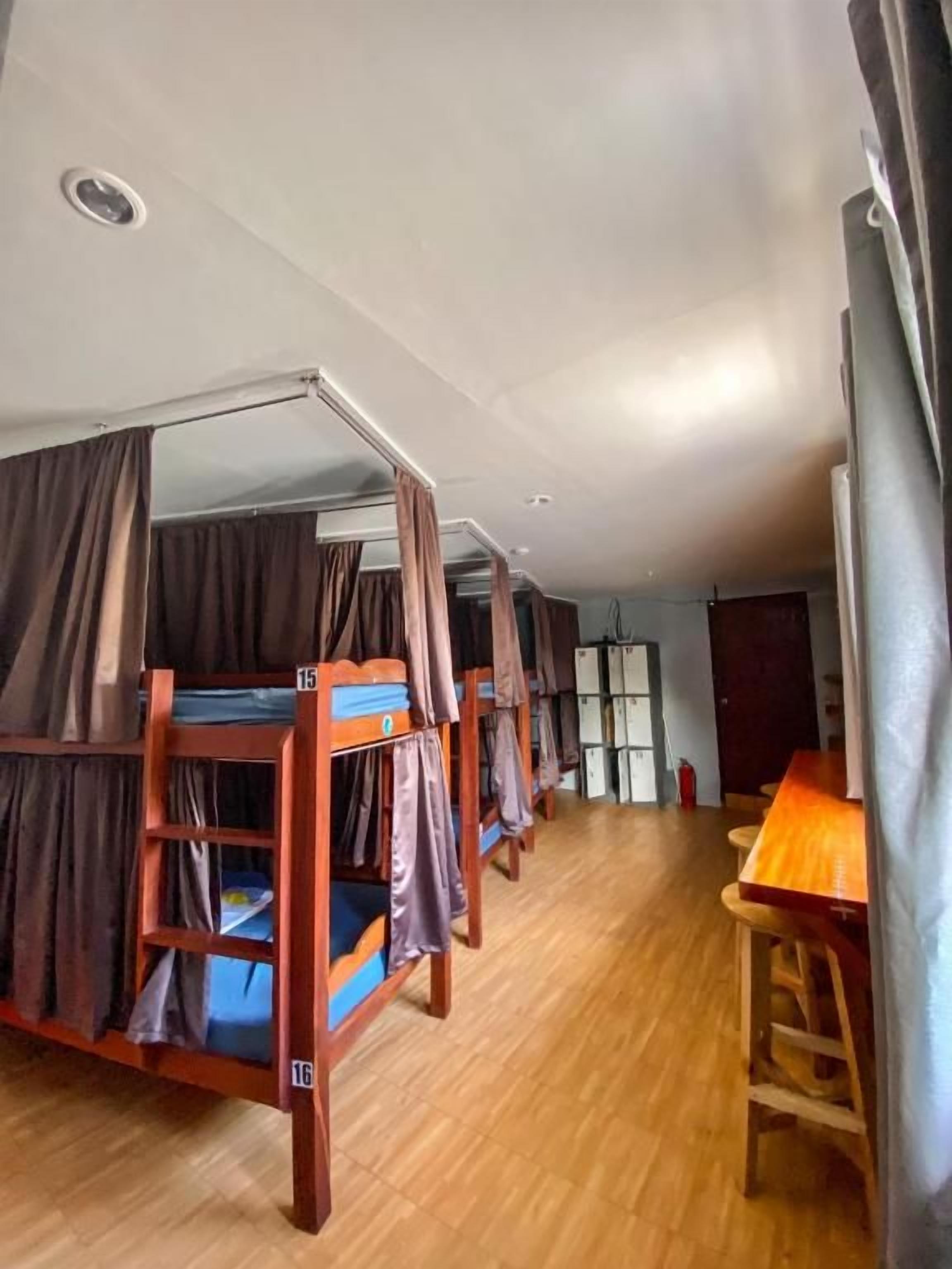 Une chambre de dortoir avec des lits superposés, une table en bois et un extincteur.
