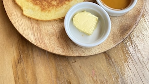 Une table en bois avec des crêpes, du sirop et du beurre.