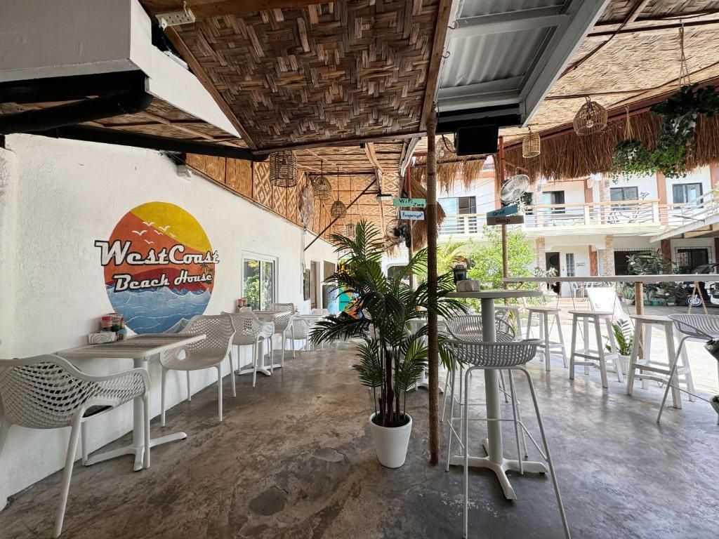 Una casa de playa con mobiliario exterior, un mural grande y un techo de paja.