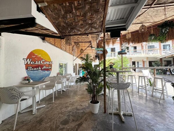 A beach house with outdoor seating, a large mural, and a thatched roof. - Westcoast Guest House (Moalboal)