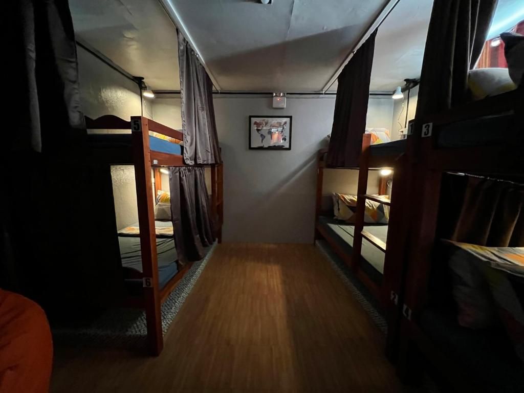 Un pasillo estrecho con literas a ambos lados, un cuadro en la pared y una lámpara en el techo.