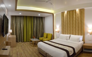 A hotel room with a bed, a desk, a chair, a TV, and curtains.
