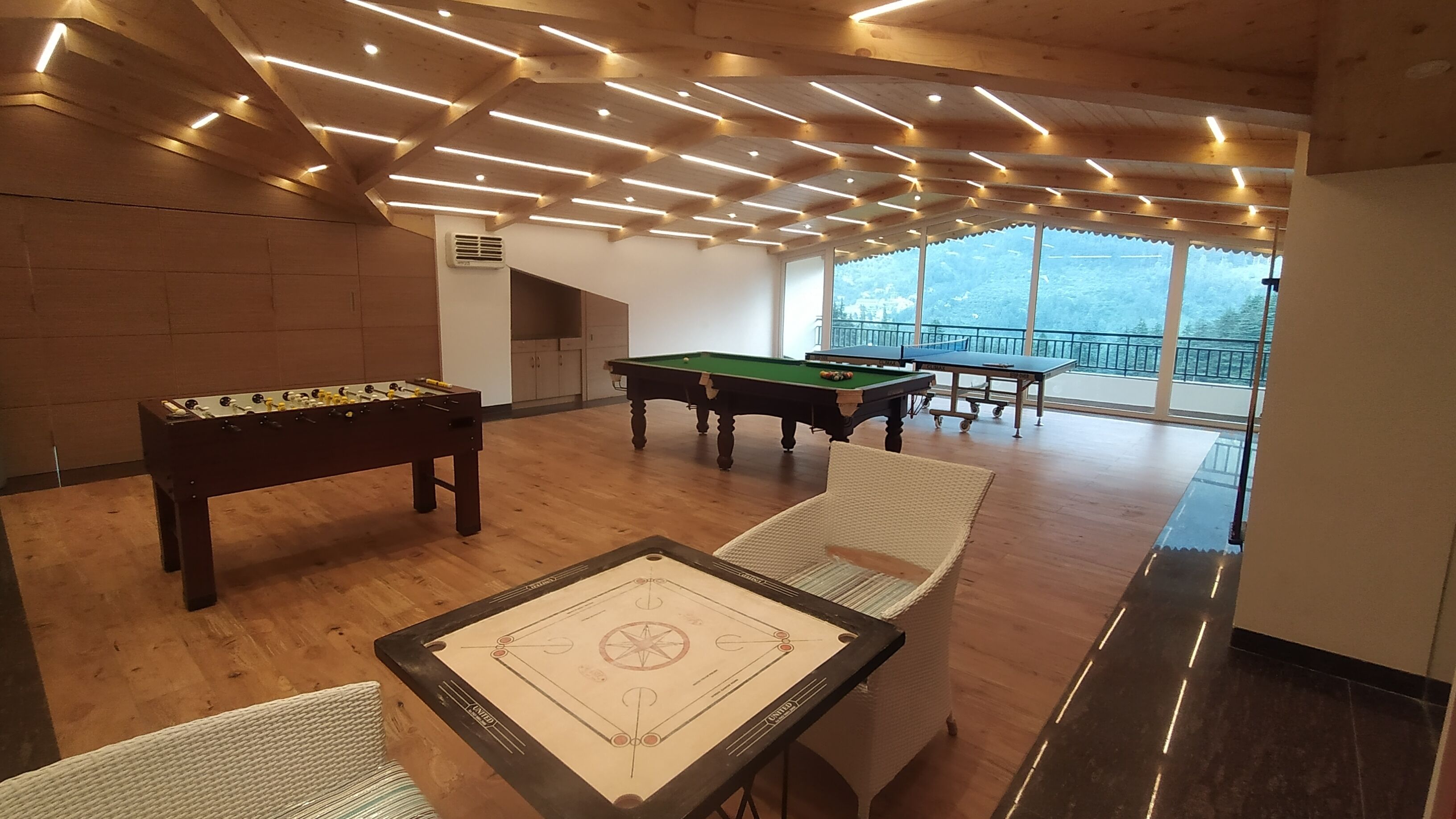 A billiards room with a pool table, a foosball table, and a foosball table with a star design.