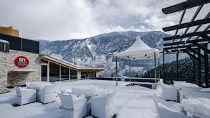 Un espace extérieur aménagé avec des meubles en osier, une tente et un décor de montagne, le tout recouvert de neige.