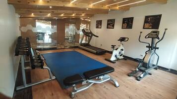 Ein Fitnessraum mit Laufband, Crosstrainer und einer Gewichtshebench.