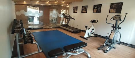 A gym with a treadmill, elliptical, and weight bench.