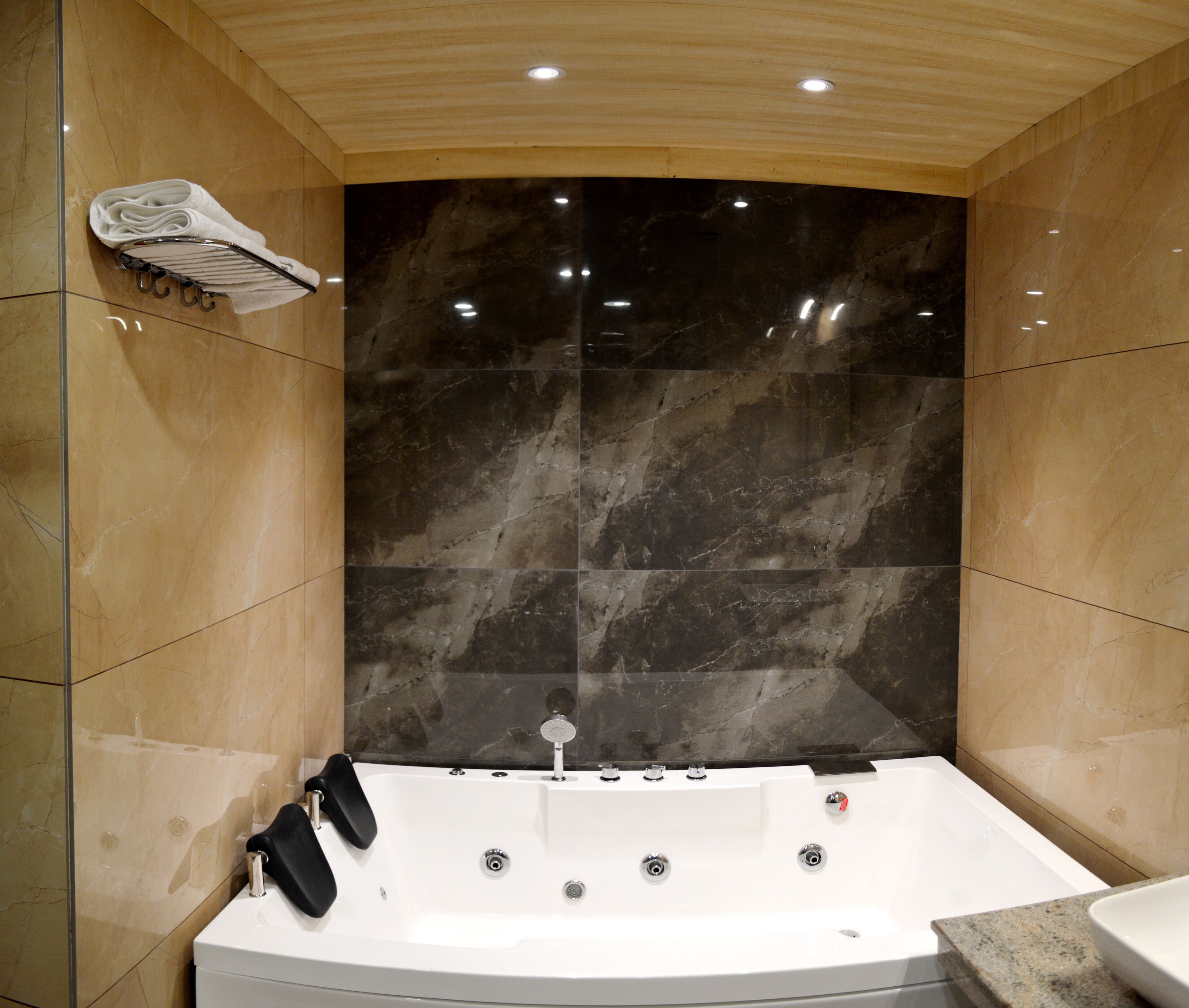 Un baño moderno con una bañera grande, paredes de mármol y techo de madera.