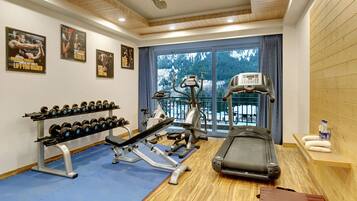 A gym with exercise equipment, a treadmill, and a rack of dumbbells.