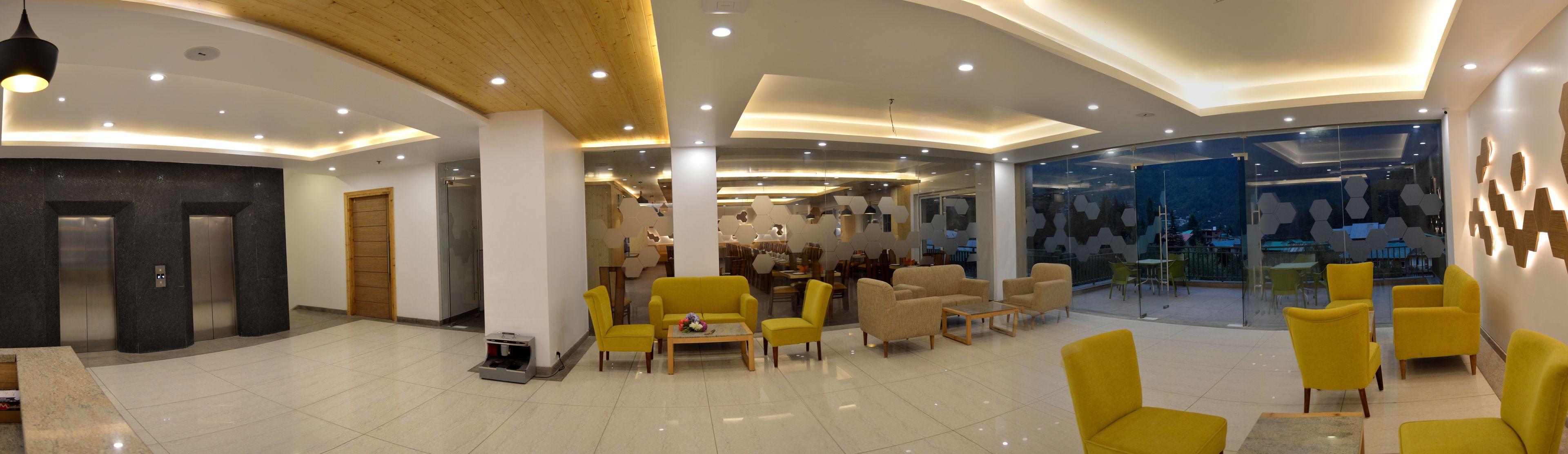 A modern lobby with a curved ceiling, recessed lighting, a reception desk, and yellow seating areas.