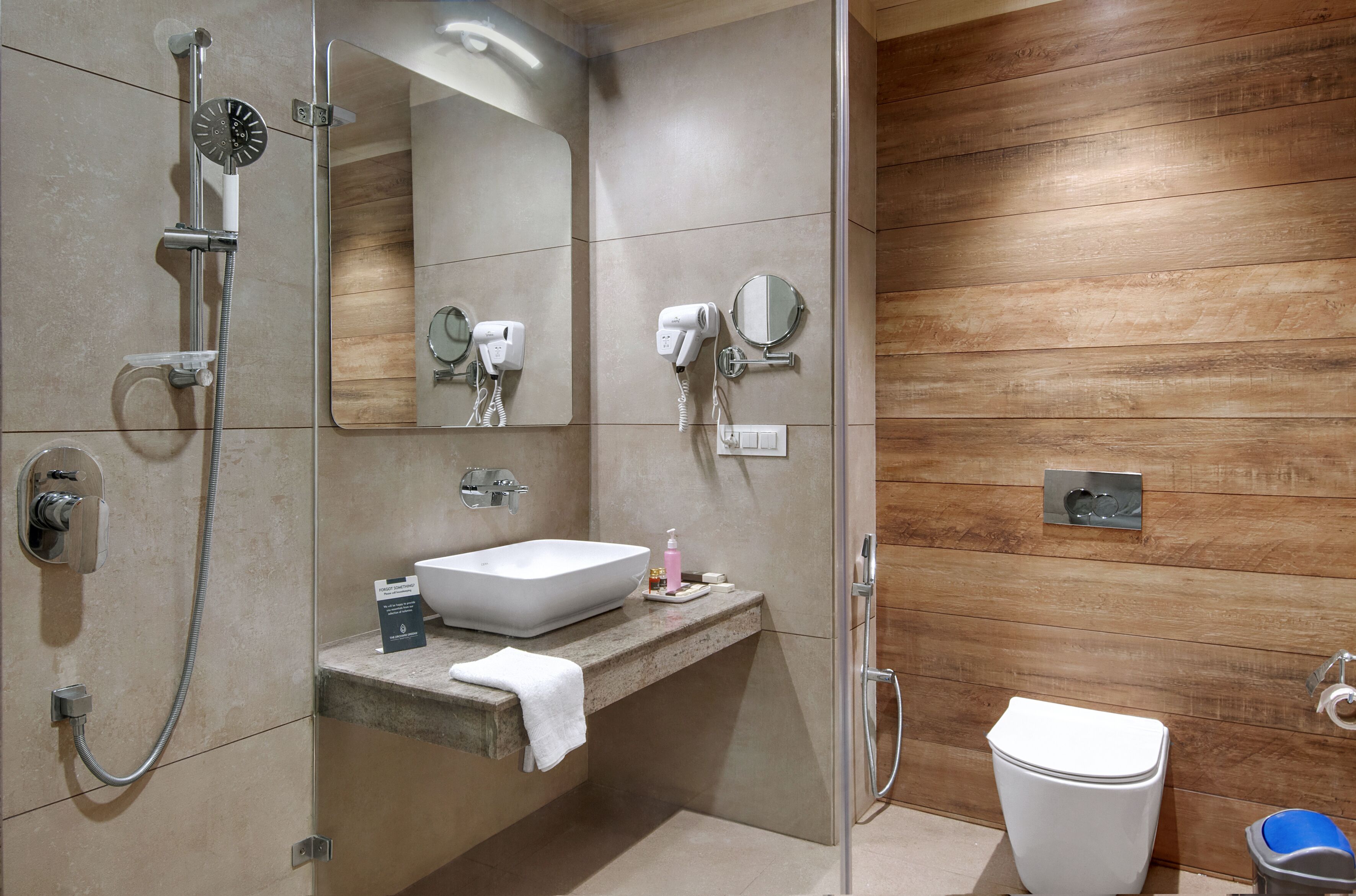 A modern bathroom with a built-in sink, a handheld showerhead, a toilet, and a mirror.