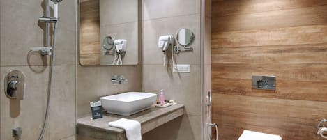 A modern bathroom with a built-in sink, a handheld showerhead, a toilet, and a mirror.