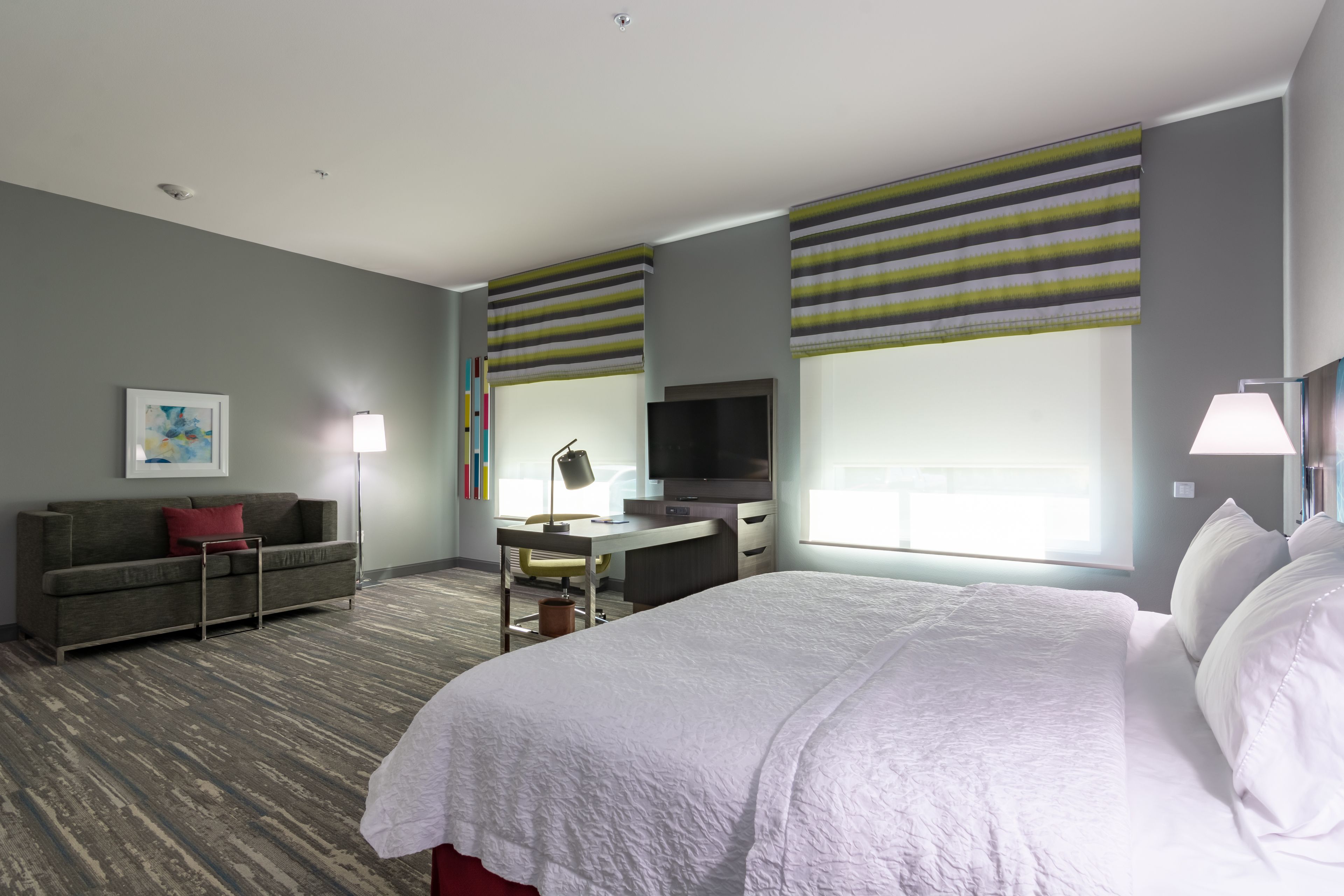 Una habitación de hotel con una cama grande, un escritorio, una televisión y un sofá.