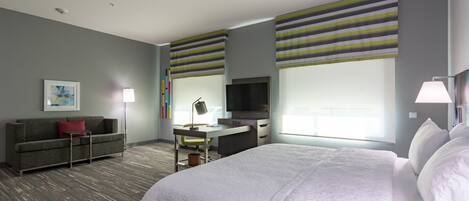 Una habitación de hotel con una cama grande, un escritorio, una televisión y un sofá.