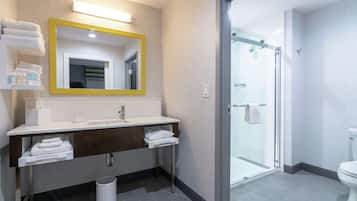 A modern bathroom with a large mirror, white sink, and a glass shower enclosure.