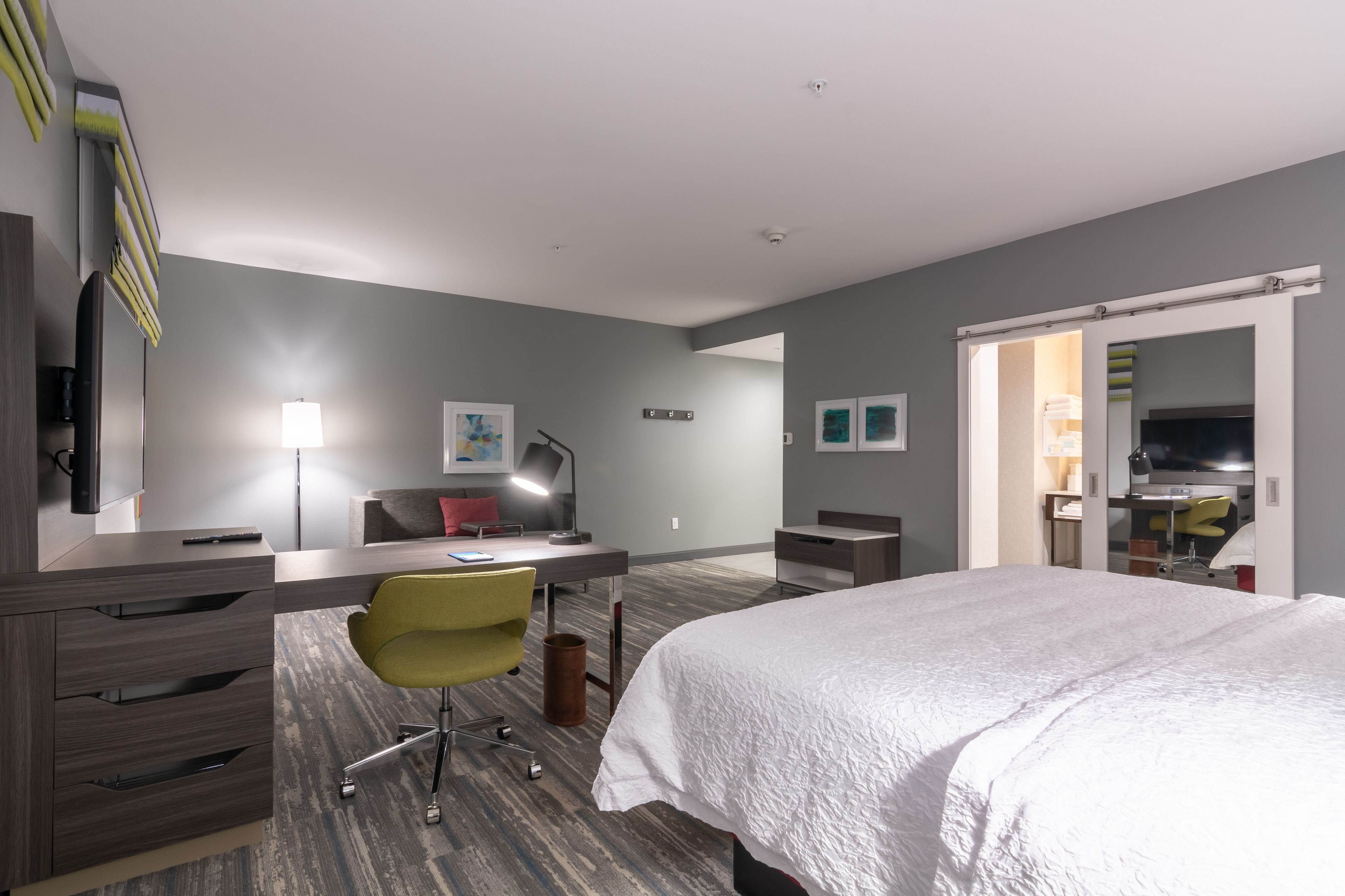 Une chambre d’hôtel moderne dotée d’un grand lit, d’un bureau avec une chaise, d’une télévision à écran plat et d’une armoire.