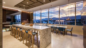 A modern kitchen with a large island, bar stools, and a city view.