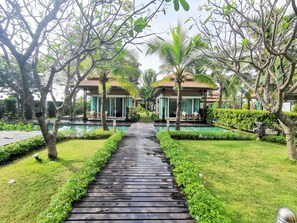 A pathway leading to two villas with a pool, surrounded by lush greenery and palm trees. - Keang Kluen Talay Resort (Phetchaburi)