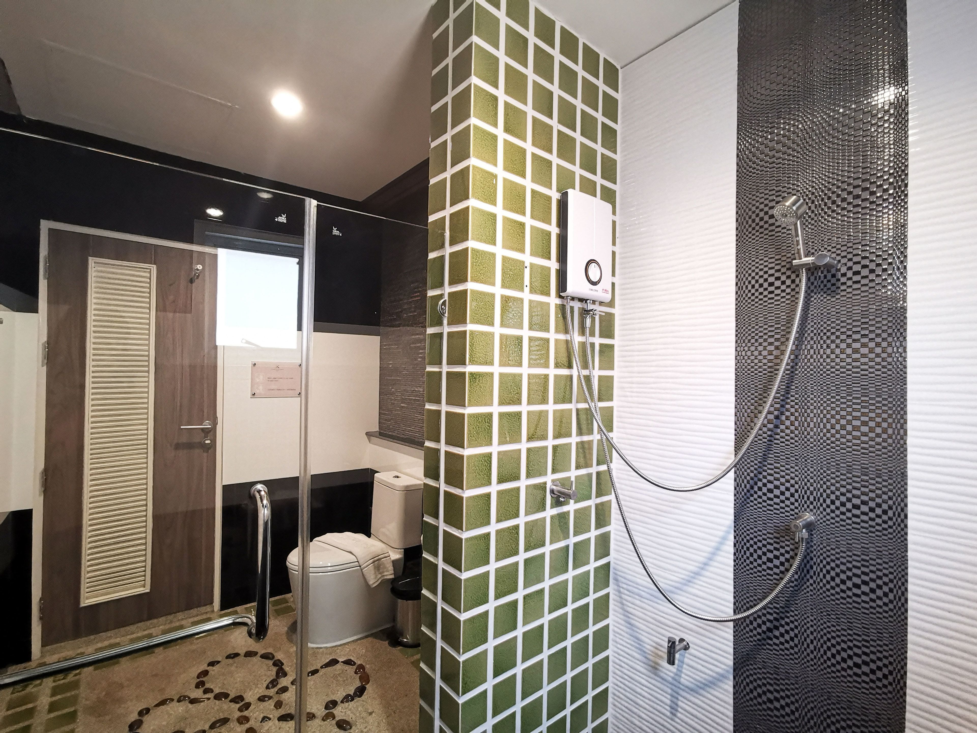 A bathroom with a toilet, a shower, and a glass-enclosed shower area.