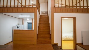 Een meerlaags houten interieur met een trap, een kitchenette en een slaapkamer.