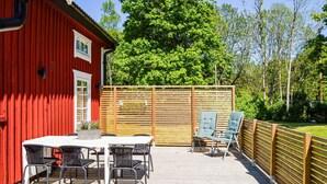 A red building with a deck, outdoor seating, and a wooden fence. - Cozy home in Herräng with WiFi (Herräng)