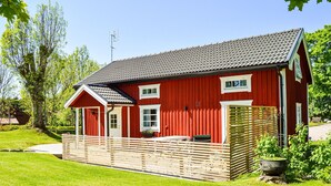 A red wooden house with a tiled roof, a front porch, and a small garden area. - Cozy home in Herräng with WiFi (Herräng)