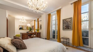 Un dormitorio con una cama grande, un escritorio, una silla, un espejo y una araña.