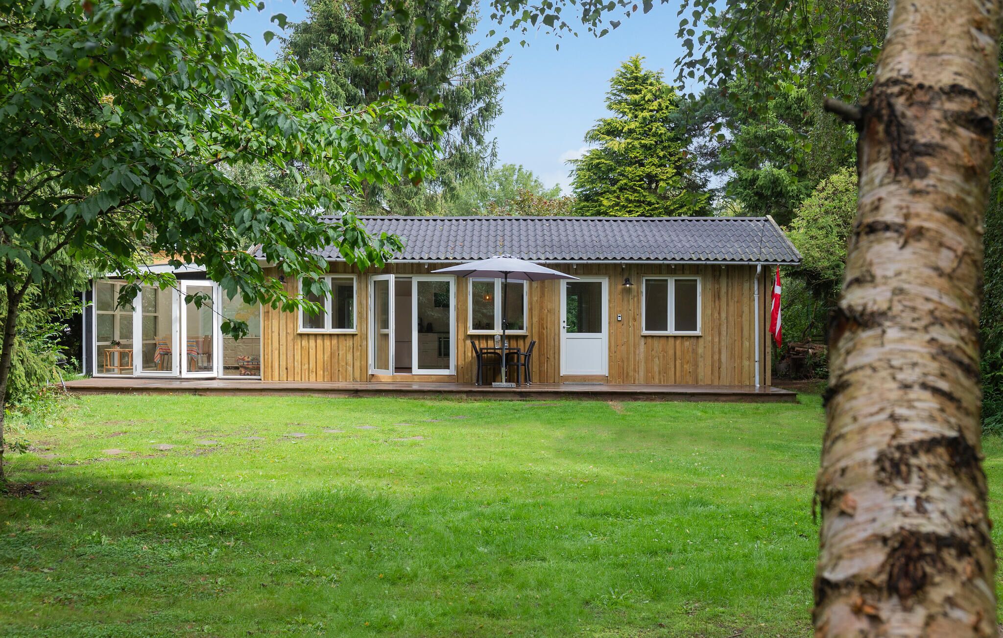 A wooden cabin with a tiled roof, large windows, and a covered patio area.