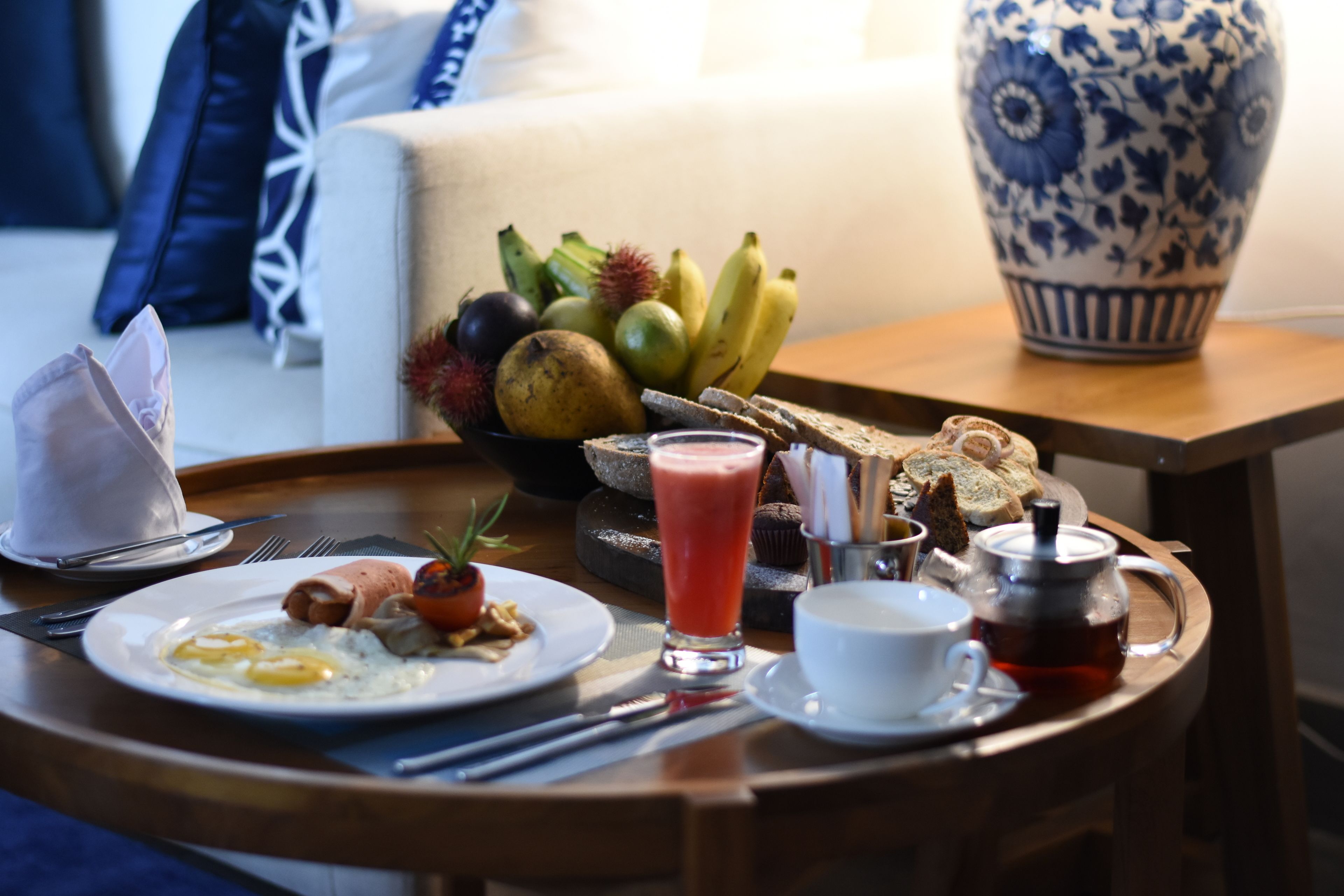 Uma bandeja de café da manhã com ovos, torradas, frutas e uma chaleira em cima de uma mesa de madeira.