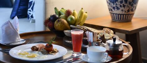 Uma bandeja de café da manhã com ovos, torradas, frutas e uma chaleira em cima de uma mesa de madeira.