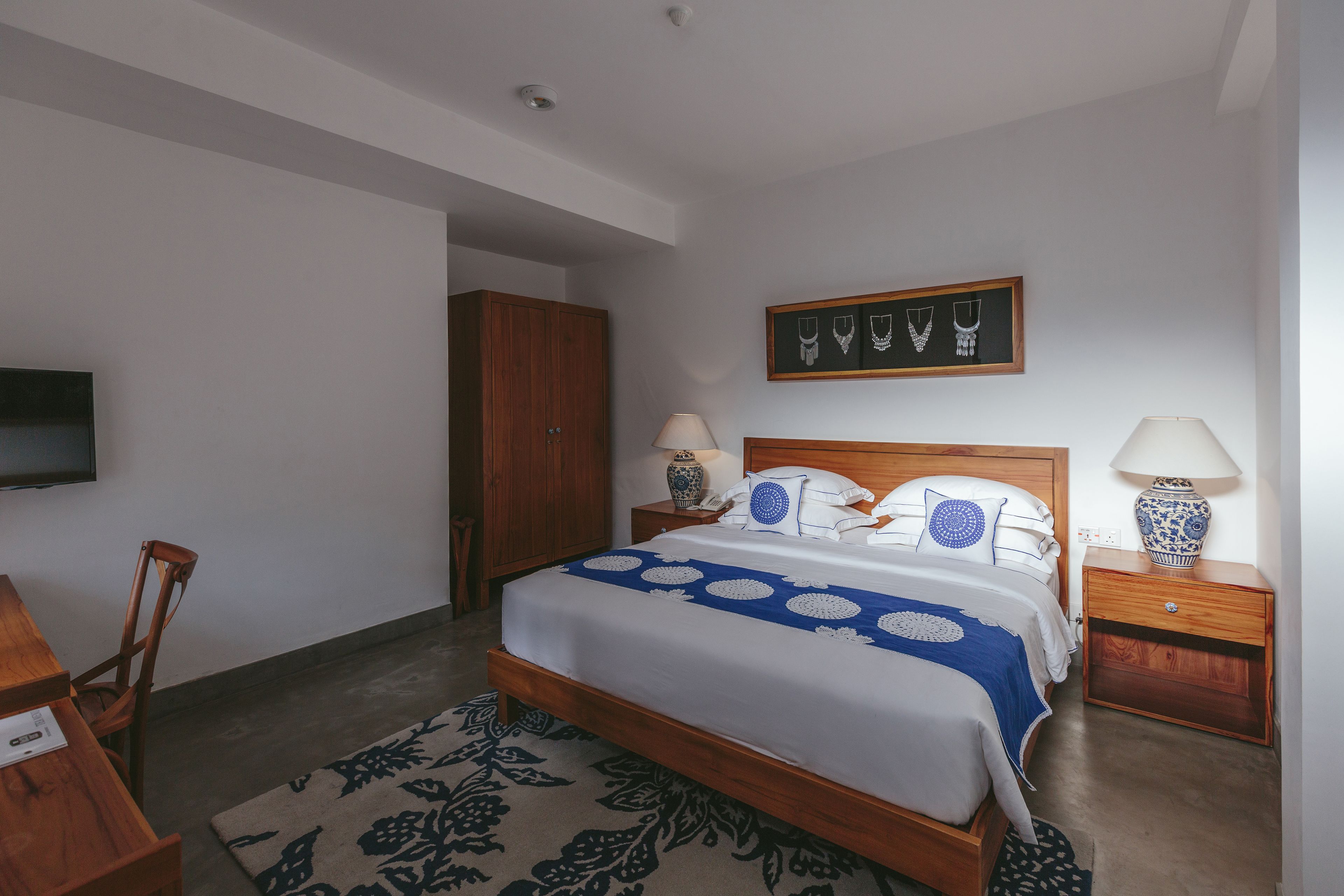 A bedroom with a wooden bed, two bedside tables with lamps, a TV mounted on the wall, and a wardrobe.