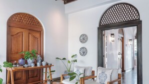 A spacious living area with wooden furniture, a large wooden door, and decorative plates on the wall. - Yara Galle Fort (Galle)