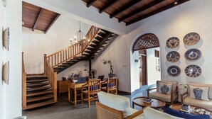A spacious living area with a wooden staircase, a dining table with chairs, and a seating area with sofas. - Yara Galle Fort (Galle)
