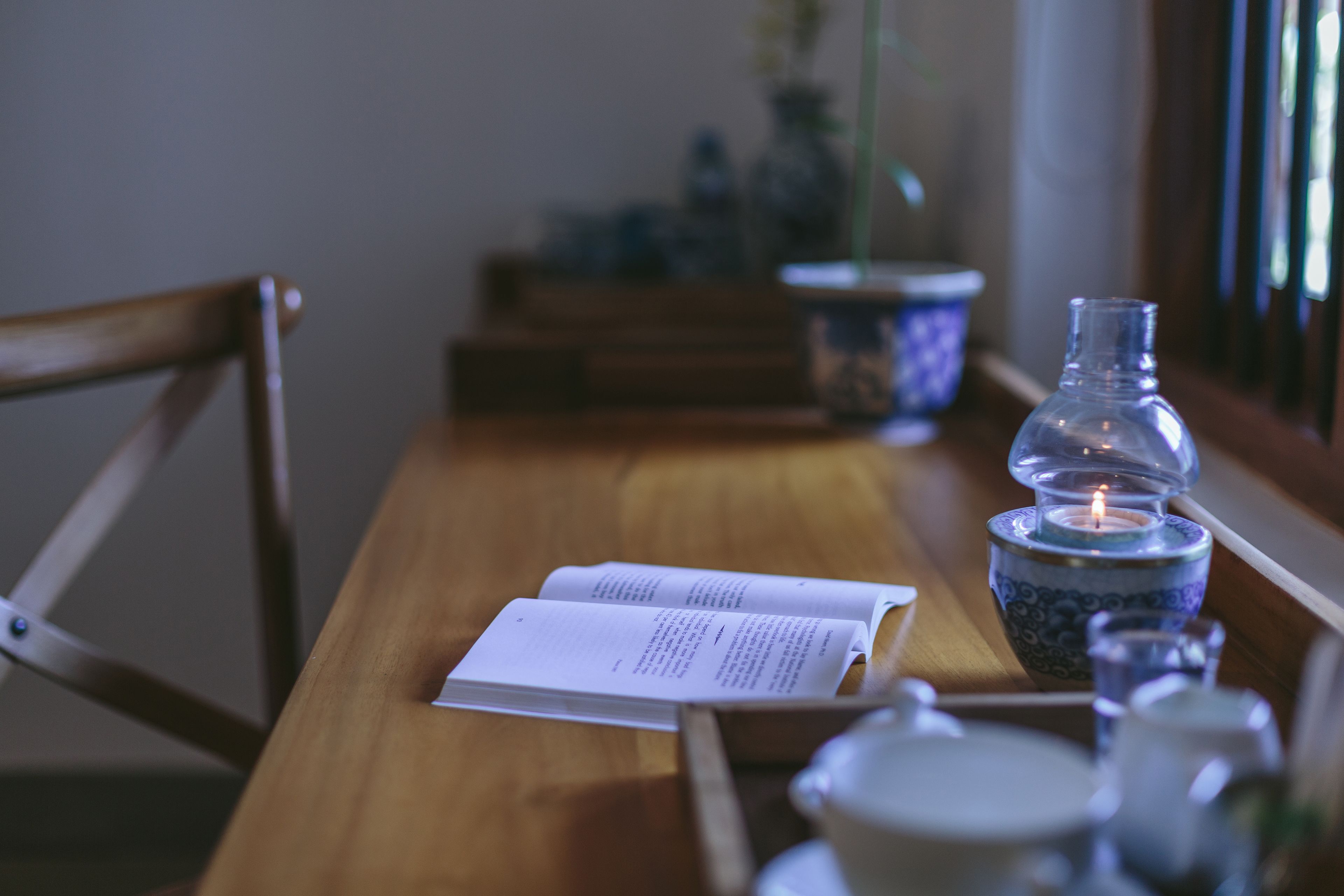 Une table en bois avec un livre, une bougie et une théière.