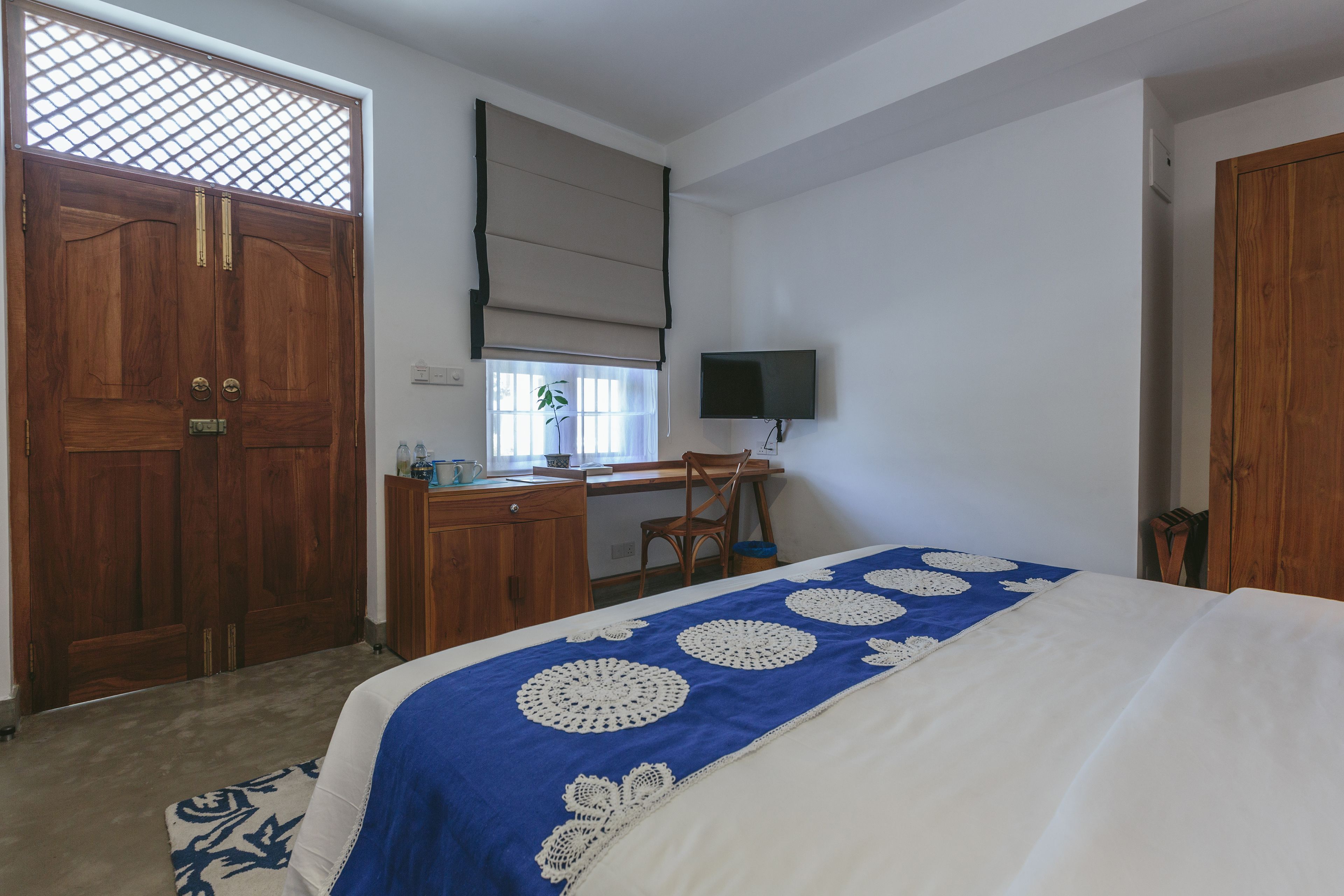 Een slaapkamer met een bed, bureau, stoel, televisie en een garderobe.