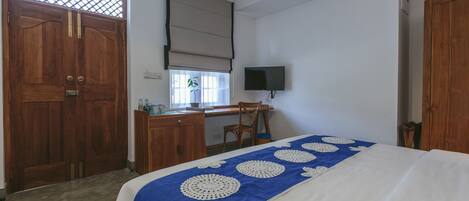 Een slaapkamer met een bed, bureau, stoel, televisie en een garderobe.