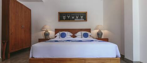 Un dormitorio con una cama de madera, dos lámparas de noche, un adorno en la pared y una alfombra estampada.