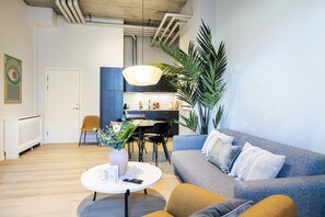 A modern living room with a grey sofa, a round coffee table, and a dining area with a white table and chairs. - The Beach apartments by Daniel&Jacob’s (Copenhagen)