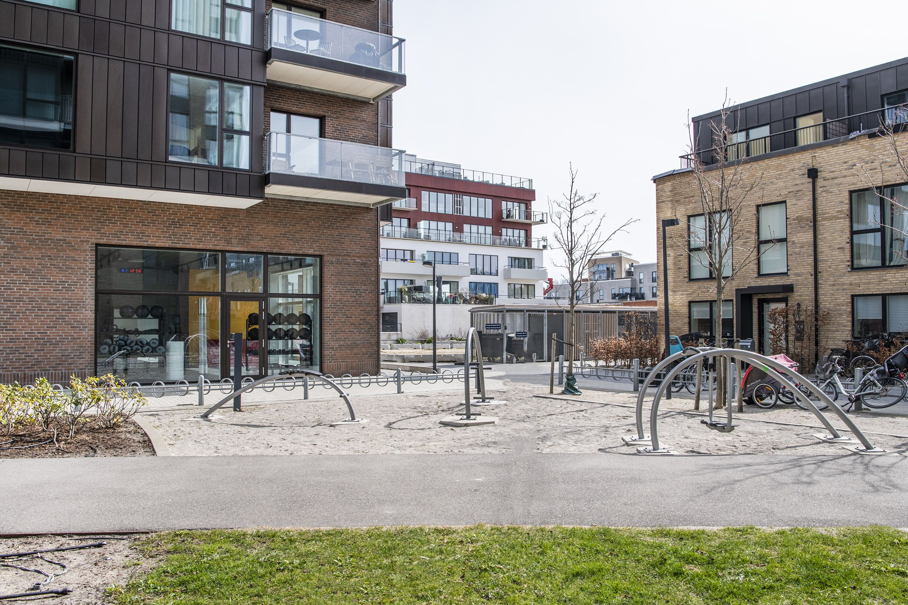 A modern building with a glass storefront and a bike parking area with metal bike racks.
