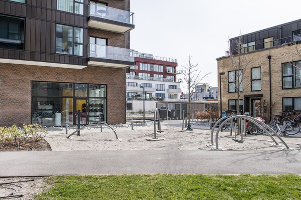 Un edificio moderno con fachada de vidrio y un área de estacionamiento para bicicletas con sujetacables metálicos.