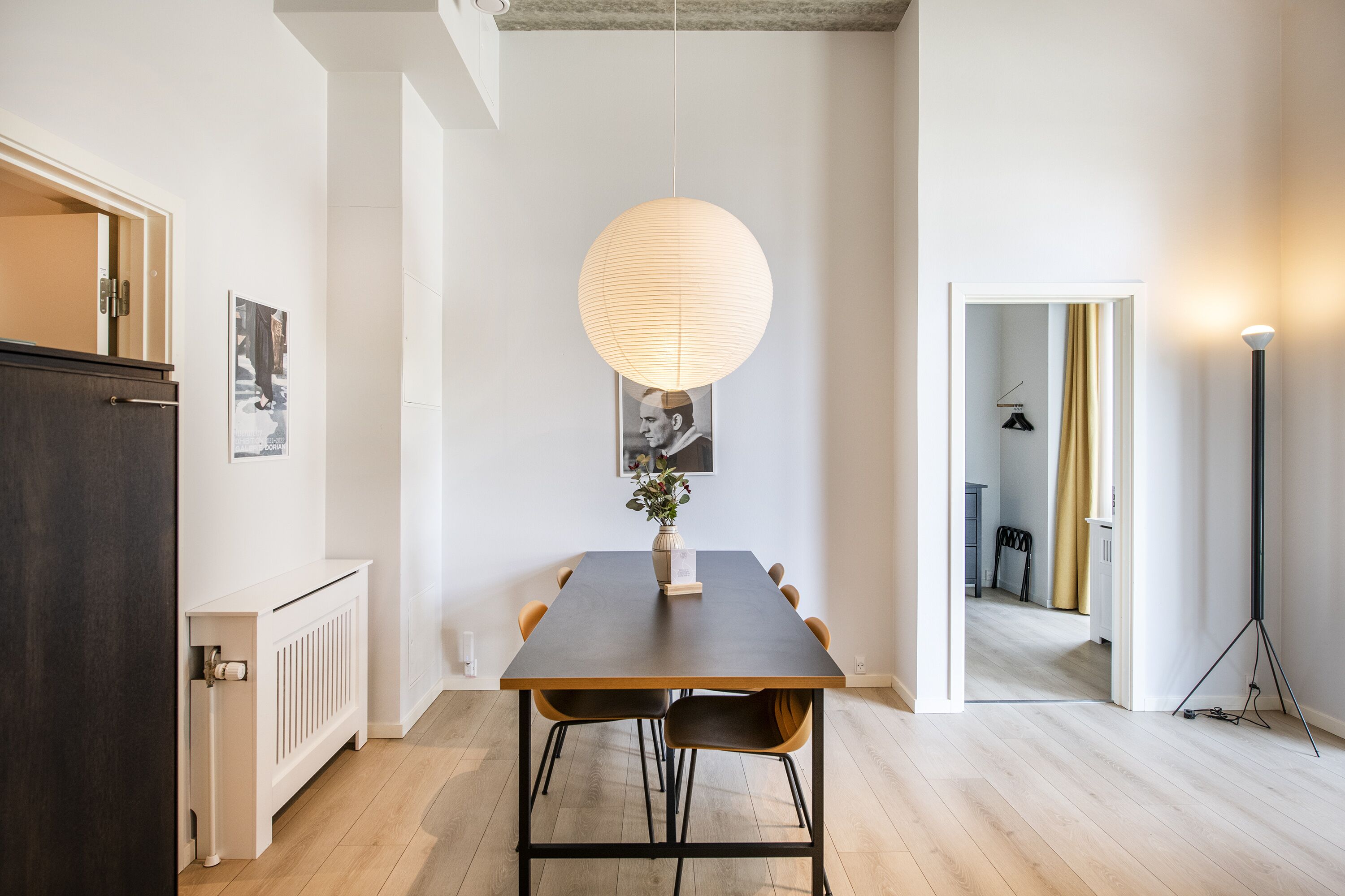 Un espace repas comprenant une table, des chaises, un luminaire suspendu et un radiateur.