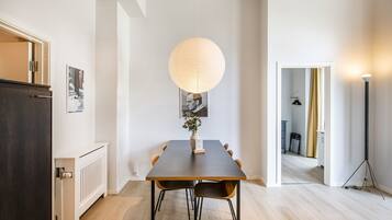 Un espace repas comprenant une table, des chaises, un luminaire suspendu et un radiateur.