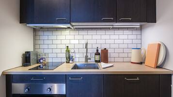 A modern kitchen with dark cabinets, a stainless steel sink, and a wooden countertop.