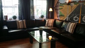 Een moderne woonkamer met een hoekbank, een glazen salontafel en een muurschildering van een weg.